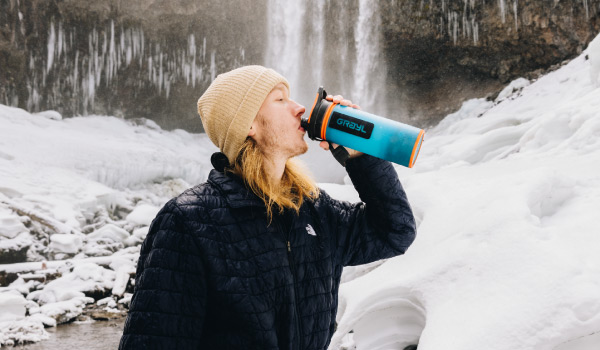 雪の中で、ボトルから水を飲む女性の写真(BALBL)